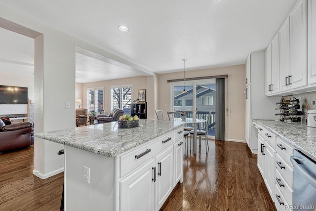 kitchen with decorative light fixtures, a kitchen bar, dishwasher, and white cabinetry