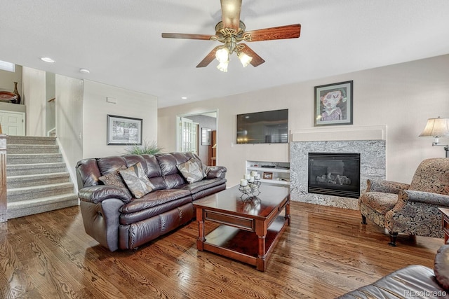 living room with hardwood / wood-style flooring, a high end fireplace, and ceiling fan