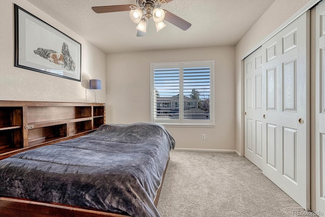 bedroom with a closet, ceiling fan, light colored carpet, and a textured ceiling