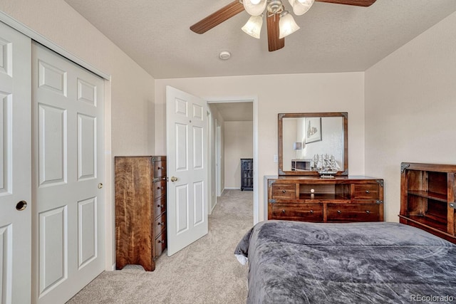 bedroom featuring a closet, ceiling fan, light colored carpet, and a textured ceiling