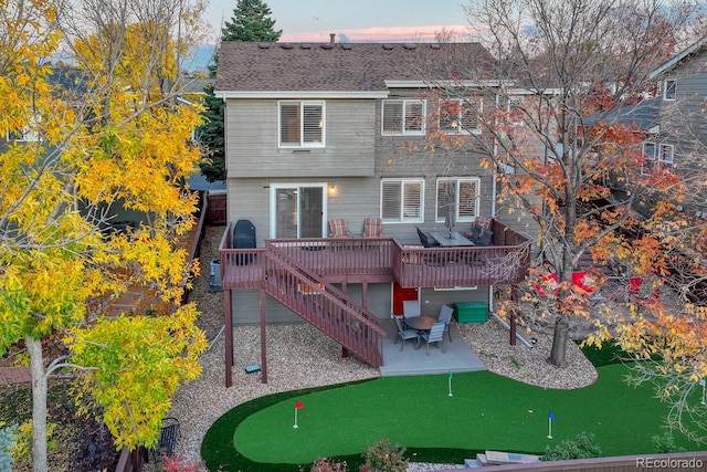 back house at dusk featuring a patio and a deck