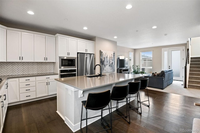 11350 W Grand Ave, Littleton, CO 80127 - kitchen with tasteful backsplash, white cabinetry, appliances with stainless steel finishes, a sink, and open floor plan