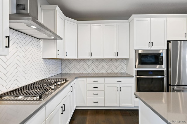 11350 W Grand Ave, Littleton, CO 80127 - kitchen featuring wall chimney range hood, white cabinetry, dark wood finished floors, stainless steel appliances, and decorative backsplash
