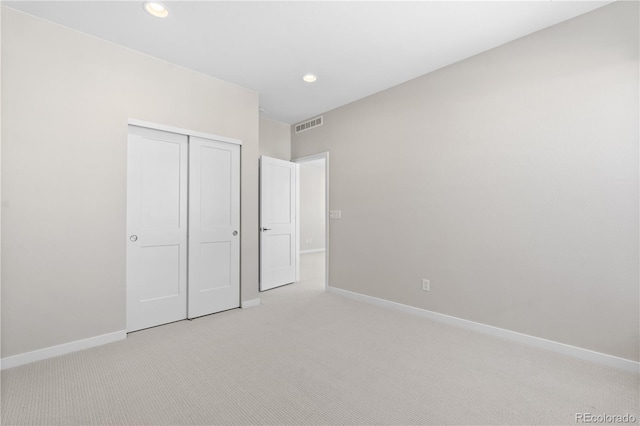 unfurnished bedroom with light colored carpet and a closet