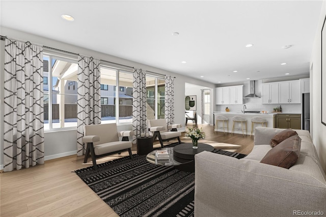 living room with washer / dryer, sink, a wealth of natural light, and light hardwood / wood-style flooring