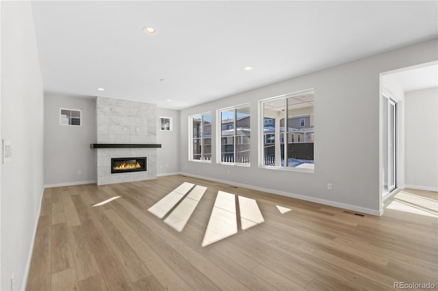 unfurnished living room with a tiled fireplace and light hardwood / wood-style flooring