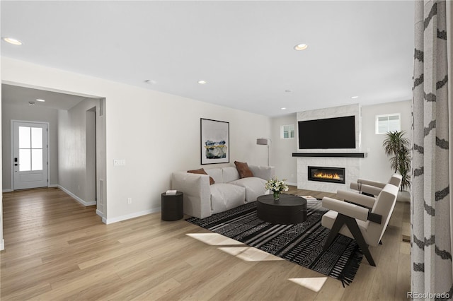 living room with a tiled fireplace and light wood-type flooring