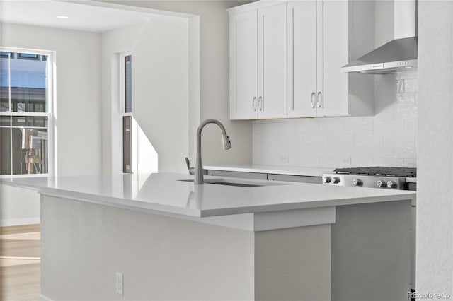 kitchen featuring sink, white cabinets, wall chimney range hood, and kitchen peninsula