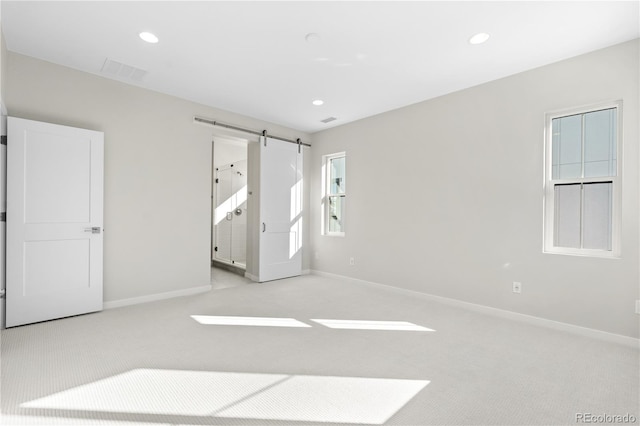 carpeted empty room with a barn door