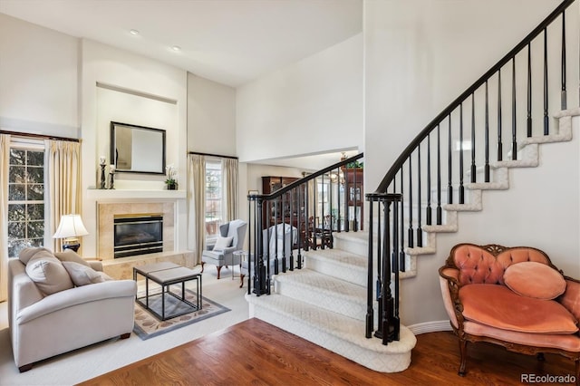 living room with a tile fireplace, a high ceiling, and hardwood / wood-style flooring