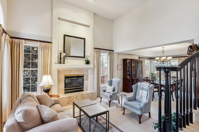 carpeted living room featuring a towering ceiling, a tile fireplace, and an inviting chandelier