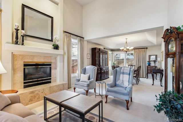 living room featuring a premium fireplace, carpet, a healthy amount of sunlight, and a notable chandelier