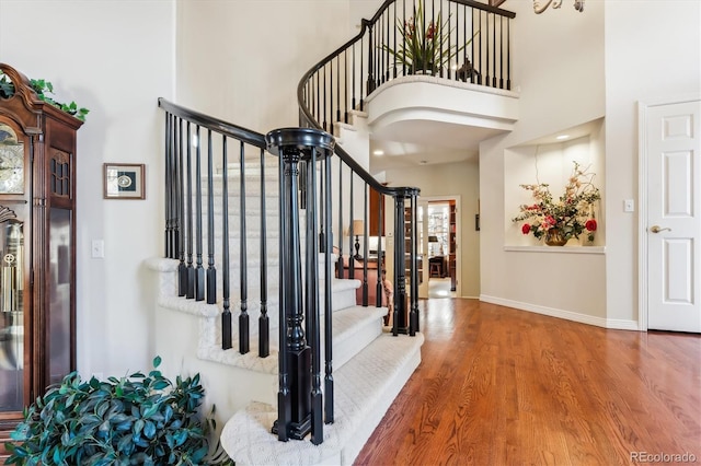 staircase featuring a high ceiling and wood-type flooring