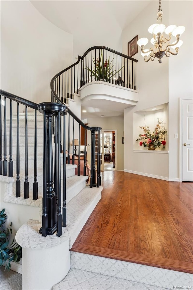 foyer featuring a chandelier, a towering ceiling, and wood-type flooring