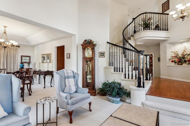 living room with a high ceiling, an inviting chandelier, and light hardwood / wood-style flooring