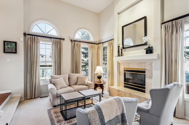 living area featuring a tile fireplace, light colored carpet, and a high ceiling