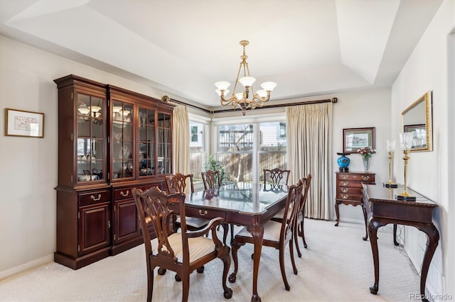 carpeted dining room featuring a raised ceiling and an inviting chandelier