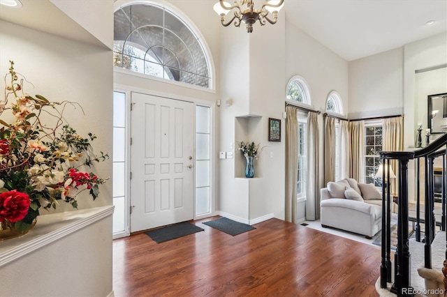 entryway featuring wood-type flooring, a high ceiling, and a notable chandelier