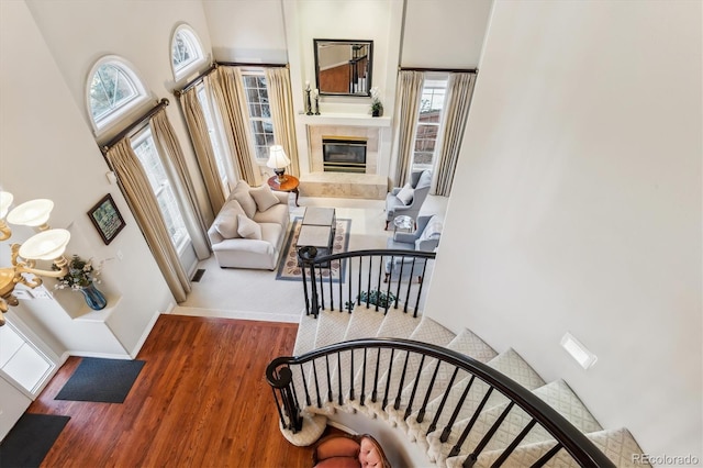 stairway featuring a fireplace, a towering ceiling, and hardwood / wood-style flooring