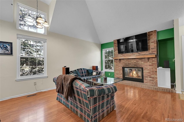 14110 E Dickinson Dr Unit A, Aurora, CO 80014 - living room featuring wood finished floors, a chandelier, high vaulted ceiling, a fireplace, and baseboards