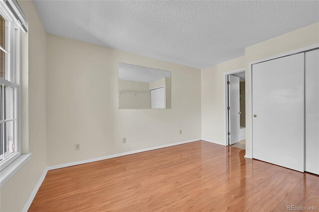 14110 E Dickinson Dr Unit A, Aurora, CO 80014 - unfurnished bedroom with wood finished floors, a textured ceiling, baseboards, and a closet