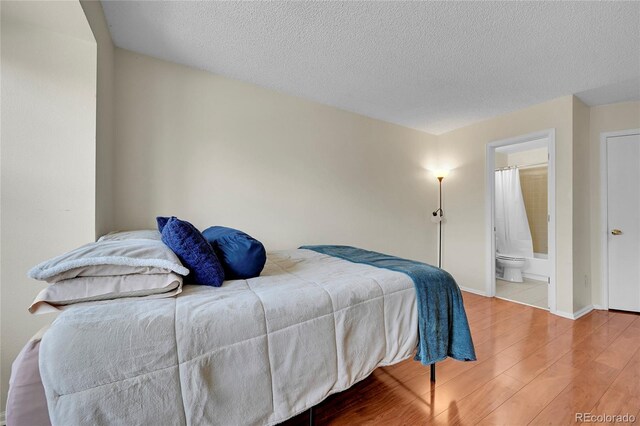 14110 E Dickinson Dr Unit A, Aurora, CO 80014 - bedroom featuring wood finished floors, a textured ceiling, baseboards, and ensuite bath