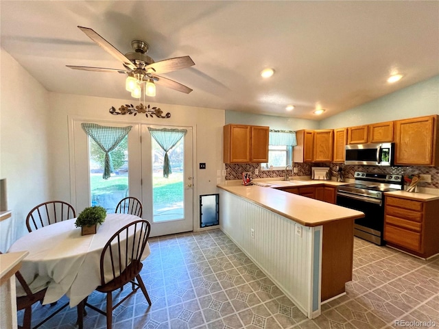 kitchen with kitchen peninsula, ceiling fan, stainless steel appliances, and tasteful backsplash