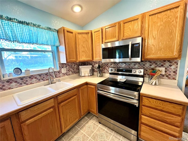 kitchen with lofted ceiling, light tile patterned floors, sink, tasteful backsplash, and stainless steel appliances