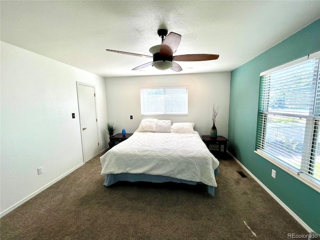 bedroom with dark colored carpet, ceiling fan, and a textured ceiling