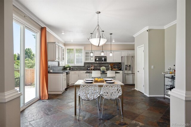 16690 Amberstone Way, Parker, CO 80134 - kitchen with appliances with stainless steel finishes, stone tile floors, backsplash, ornamental molding, and pendant lighting