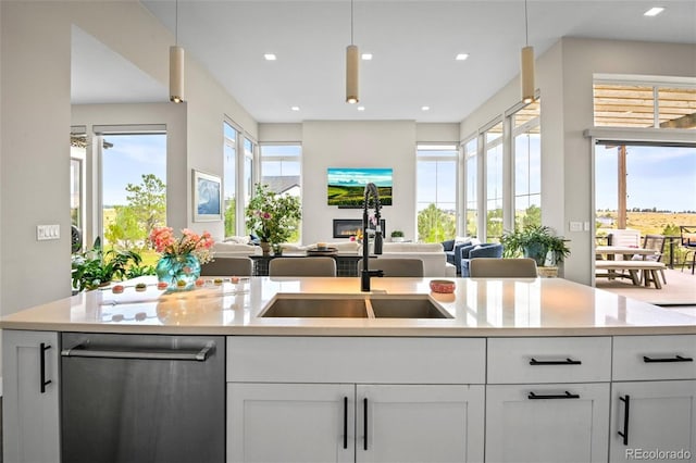 kitchen featuring sink, dishwasher, white cabinets, and pendant lighting