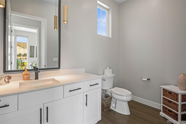 bathroom with wood-type flooring, a wealth of natural light, toilet, and vanity