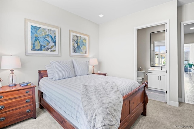 bedroom with ensuite bathroom and light carpet