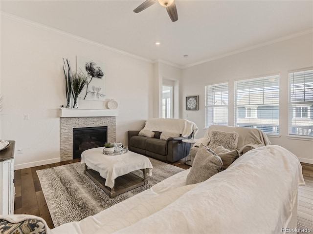 living room with dark wood-type flooring, ceiling fan, ornamental molding, and a fireplace