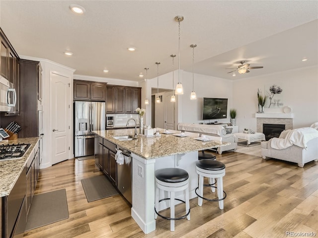 kitchen featuring stainless steel appliances, light stone countertops, a large island, and sink