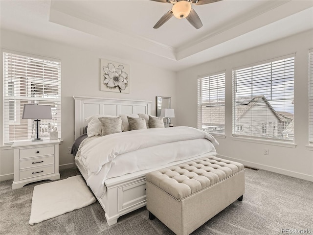 bedroom featuring ceiling fan, a tray ceiling, and carpet