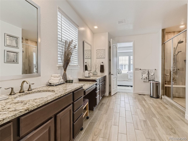 bathroom featuring hardwood / wood-style flooring, vanity, and a shower with door