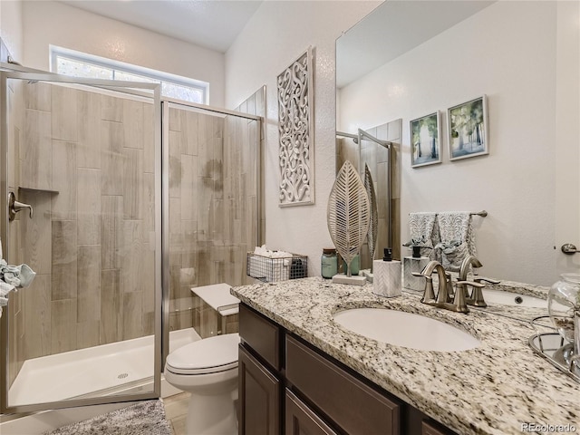 bathroom with vanity, a shower with shower door, and toilet