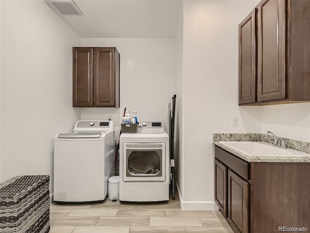 washroom with cabinets, washing machine and dryer, and sink