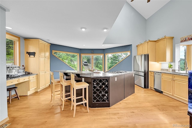14980 Elk Mountain Trl, Littleton, CO 80127 - kitchen with light brown cabinets, appliances with stainless steel finishes, light wood-style floors, a kitchen island, and recessed lighting