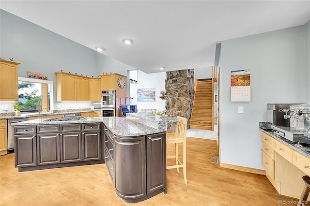 14980 Elk Mountain Trl, Littleton, CO 80127 - kitchen featuring stainless steel appliances, light wood finished floors, a breakfast bar area, light brown cabinets, and light stone countertops
