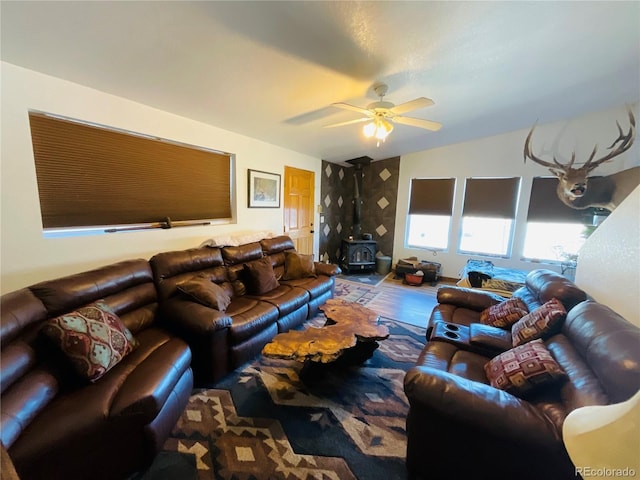 living room with a wood stove, ceiling fan, and wood finished floors