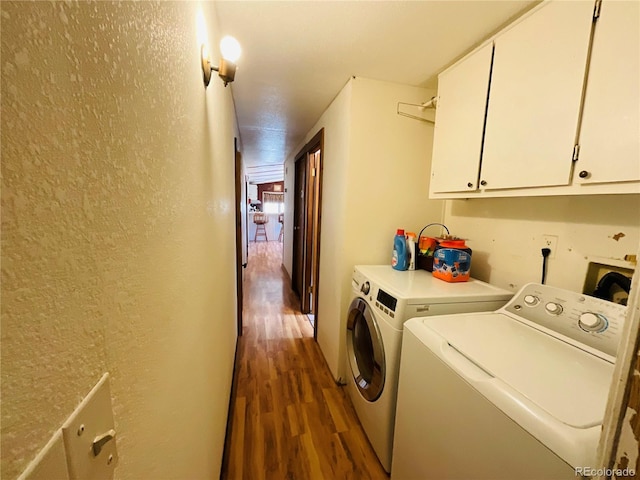 washroom featuring washer and dryer, wood finished floors, cabinet space, and a textured wall