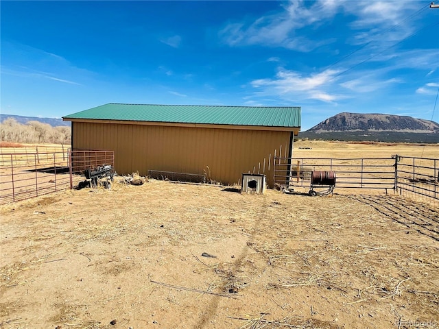 view of pole building with a rural view, a mountain view, and an exterior structure