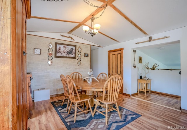 dining area featuring baseboards, an inviting chandelier, vaulted ceiling with beams, and wood finished floors