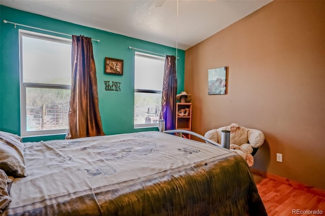 bedroom featuring baseboards, multiple windows, ceiling fan, and wood finished floors