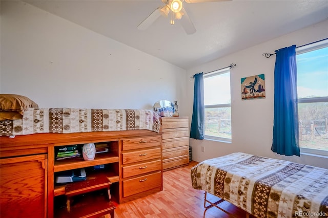 bedroom with light wood finished floors, vaulted ceiling, and ceiling fan