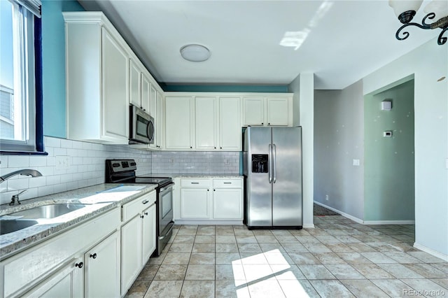 kitchen featuring tasteful backsplash, appliances with stainless steel finishes, white cabinetry, and a sink