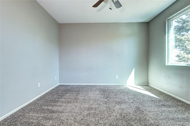 carpeted spare room featuring baseboards, a textured ceiling, and a ceiling fan