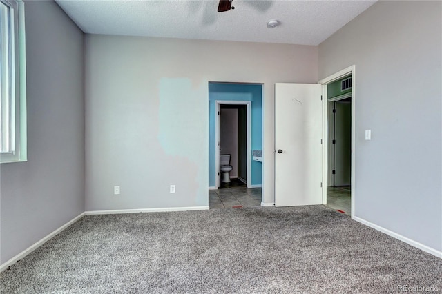 unfurnished bedroom with visible vents, baseboards, carpet, ensuite bathroom, and a textured ceiling